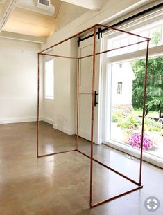 an empty room with two large windows and a metal frame on the floor in front of it