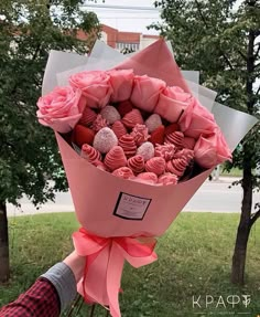 a bouquet of pink roses and chocolates wrapped in paper with a ribbon around it