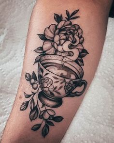 a woman's leg with a tattoo on it that has flowers and a tea cup in it