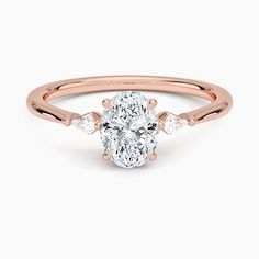 a rose gold ring with an oval cut diamond in the center and two pear shaped diamonds on