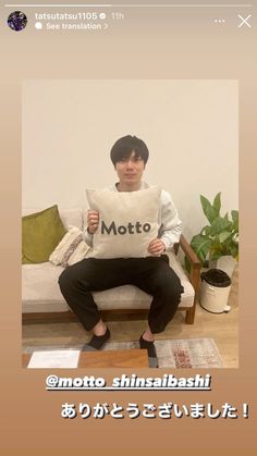 a man sitting on a couch holding a pillow with the word motto written in it