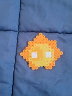 an orange and yellow beaded animal laying on top of a blue bed coverlet