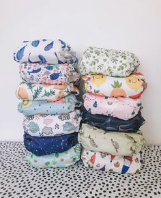 stack of baby swaddles in various colors and patterns on a polka dot tablecloth