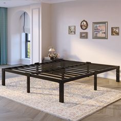 a black metal bed frame sitting on top of a rug in a living room next to a window