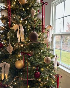 a decorated christmas tree with red and gold baubes, bows and ornaments on it