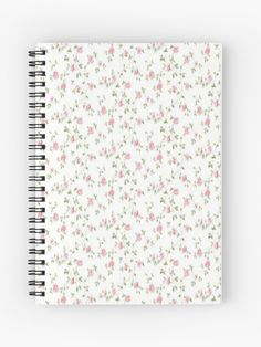 a spiral notebook with pink and green flowers on the cover, in front of a white background