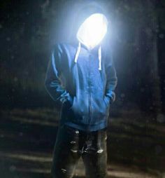 a man standing in the dark wearing a blue hoodie and holding a light on his head