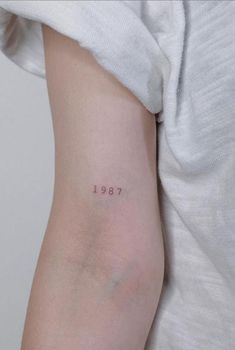 a woman with a small tattoo on her left arm and the word 1917 written in cursive font