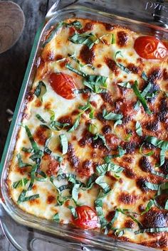 a casserole dish with tomatoes, cheese and basil