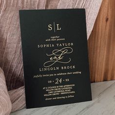 a black and gold wedding card with the word sl on it, sitting on a chair