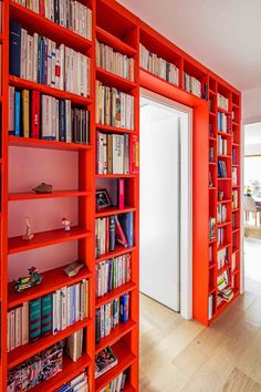 an orange bookshelf filled with lots of books next to a white door in a living room