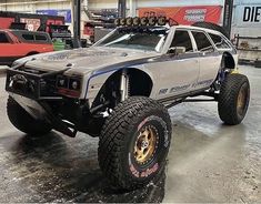 an off - road vehicle is parked in a garage with other vehicles around the area