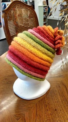 a multicolored knitted hat sitting on top of a white mannequin