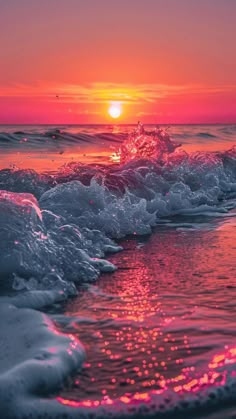 the sun is setting over the ocean with waves crashing in to shore and pink hues