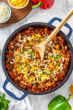 a skillet filled with mexican rice and vegetables on a marble countertop next to other ingredients