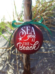 a red ornament that says sea you at the beach hanging from a pole