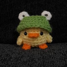 a small stuffed animal wearing a green knitted hat with eyes on it's head