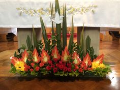 an arrangement of flowers and greenery in front of the alter at a wedding ceremony