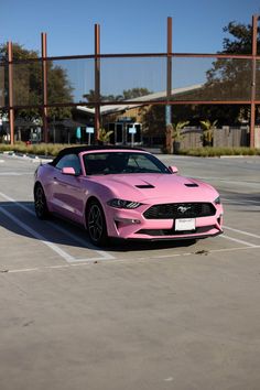 a pink mustang parked in a parking lot