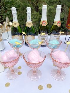 there are four glasses with ice cream in them on the table next to champagne bottles