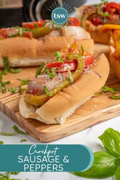 three hot dogs on buns with peppers, onions and tomatoes sitting on a cutting board