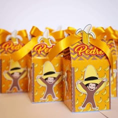 small boxes with yellow ribbon tied around them and cartoon characters on the top one is wearing a hat