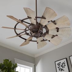 a ceiling fan with wooden blades hanging from it's center point in a living room