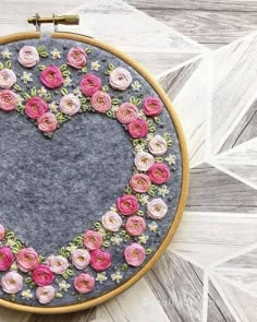 a close up of a embroidery on a hoop with flowers in the shape of a heart