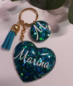 a heart shaped keychain with the word marina on it and a tassel