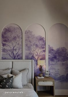 a bedroom with purple trees painted on the walls and pillows in front of it, along with a night stand