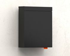 a black box mounted to the side of a white wall with an orange object on it