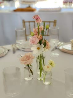 flowers are in vases on the table at a wedding reception with plates and napkins