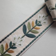 an embroidered ribbon with flowers and leaves on it