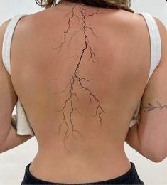 the back of a woman's body with lightning bolt tattoos on it