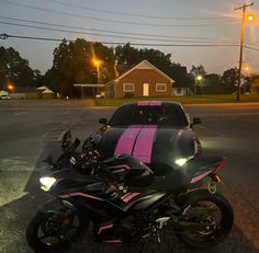 a pink and black motorcycle parked next to a car