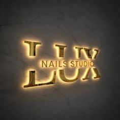 the logo for nails studio, which is lit up in gold and black with neon lights