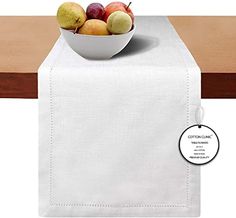 a bowl of fruit sitting on top of a table next to a white cloth napkin