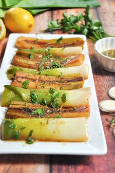 sliced up vegetables on a white plate next to some lemons and other food items