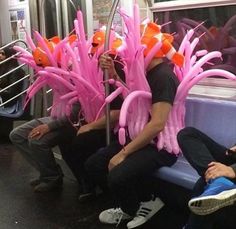 some people sitting on a train with pink and orange decorations