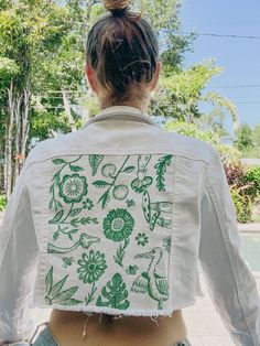 the back of a woman's shirt with green and white designs on it,