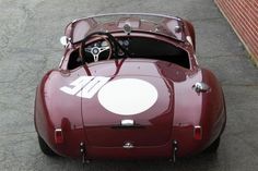 an old red sports car is parked on the street