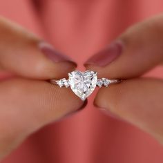 a woman's hand holding a heart shaped diamond ring