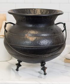 a large black vase sitting on top of a white counter