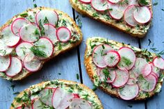 four slices of bread topped with radishes and dill on top of a blue surface