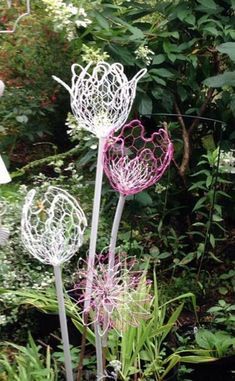 three metal flowers in the middle of a garden