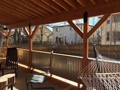 a hammock hanging from the side of a wooden porch next to a fence