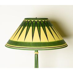 a green and yellow lamp shade on a white wall with an arrow design in the center