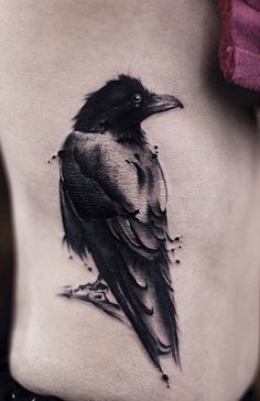 a black and white bird tattoo on the side of a woman's back stomach