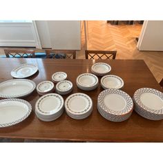 a wooden table topped with lots of white plates and bowls next to each other on top of a hard wood floor