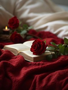 a red rose laying on top of an open book next to some flowers and candles